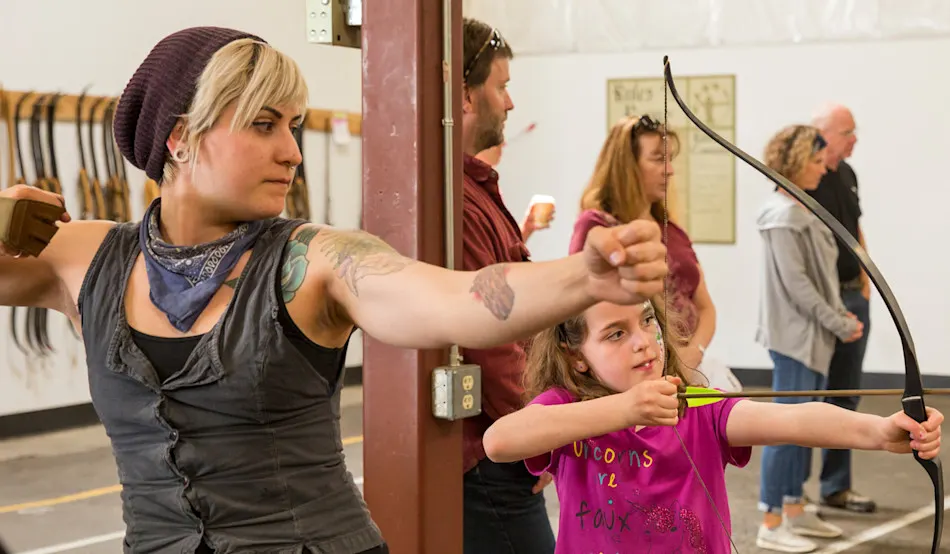 Kids and adults practicing archery with Trackers Guides